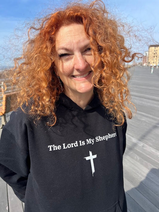 Woman wearing Psalm 23 Christian hoodie showing The Lord Is My Shepherd text and cross on black by Love1614