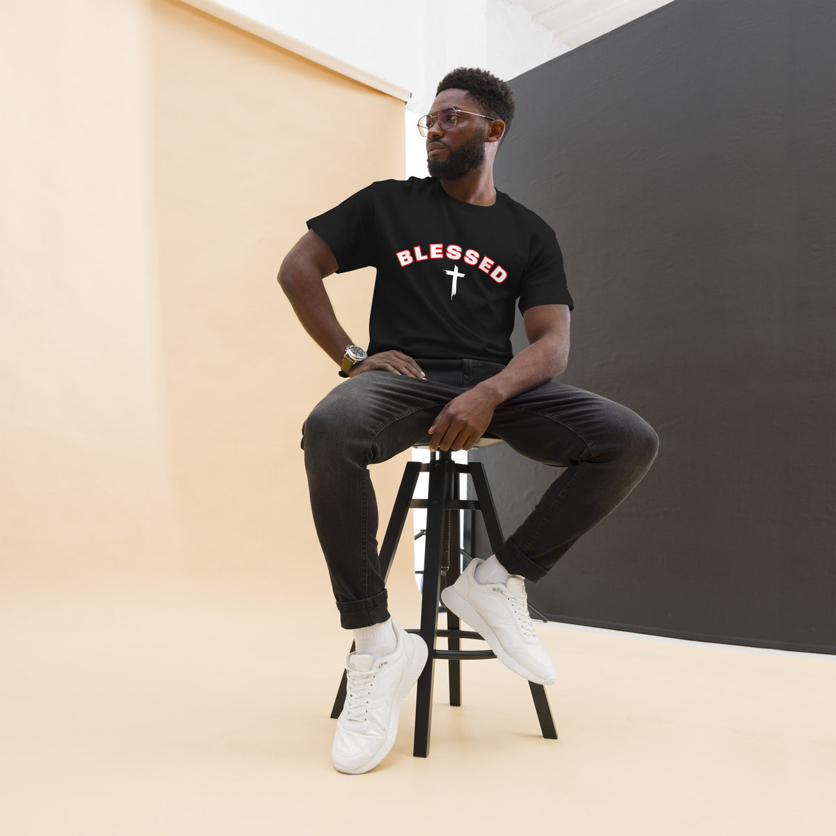 Man wearing black Blessed Cross Christian t-shirt, seated lifestyle shot